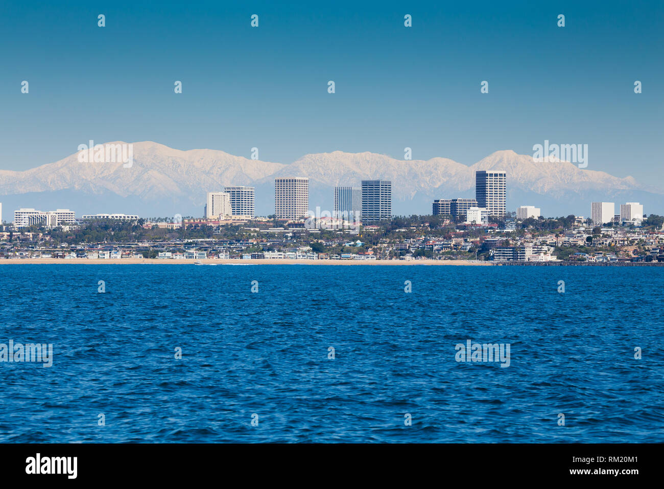 Fashion Island Newport Beach in Orange County, Kalifornien mit einem schneebedeckten Mt Baldy und der San Gabriel Mountains im Hintergrund. Stockfoto