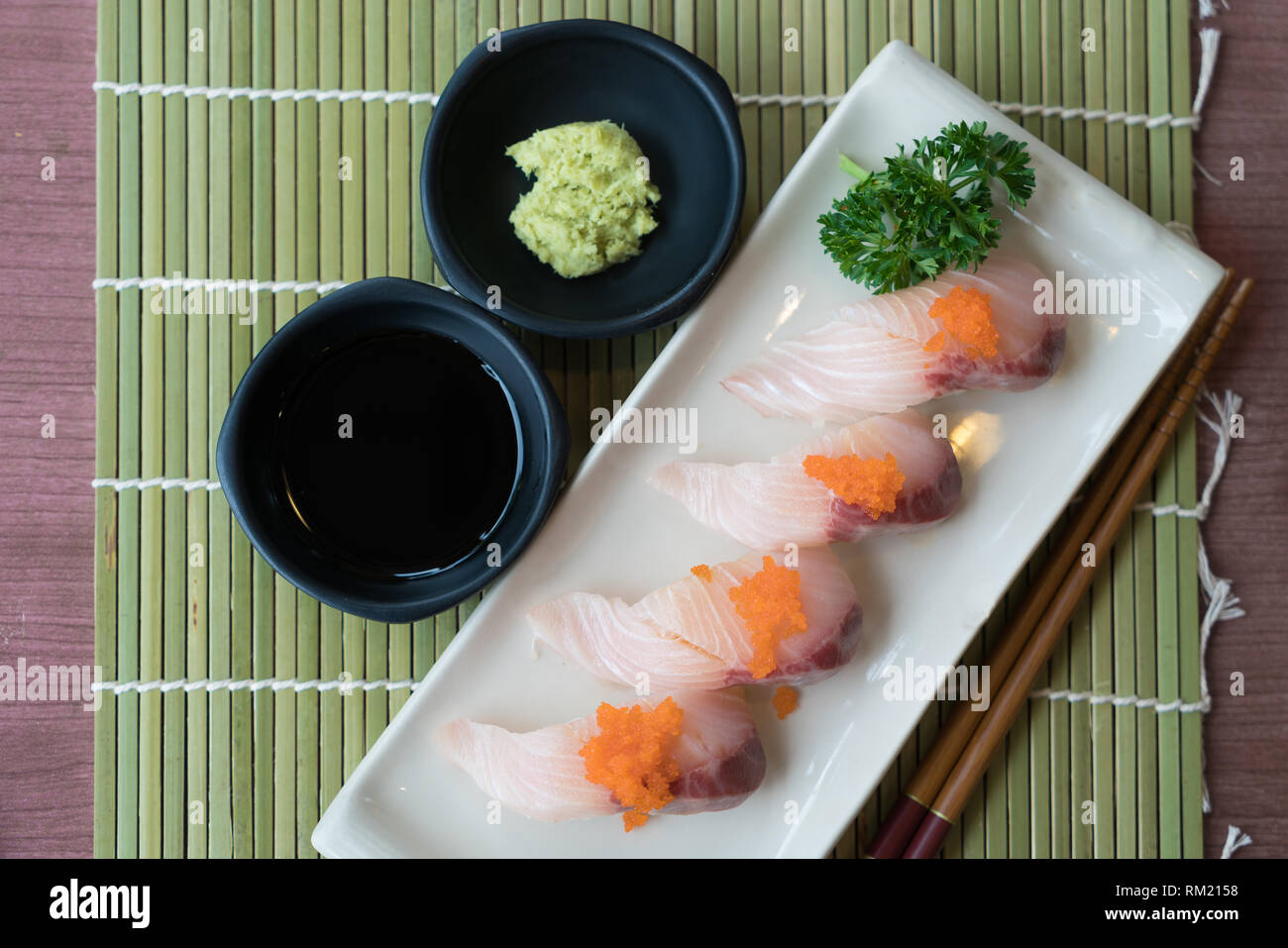 Hamachi Sushi auf weiße Platte zusammen mit japanischen Sauce und green leaf Dekoration, Japanisches Essen, Ansicht von Oben im Sushi Stockfoto