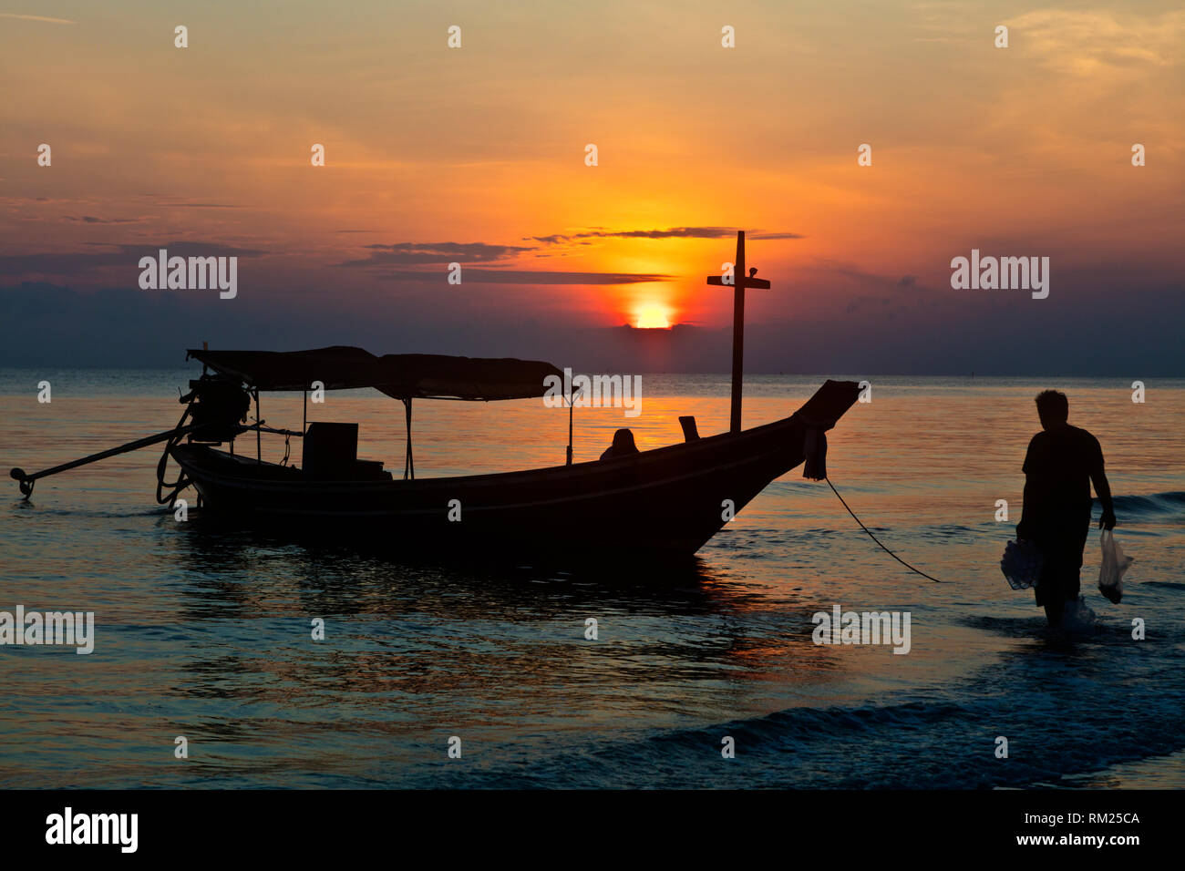 Erste Schritte auf dem longboat bei Sonnenaufgang am Strand von KHANOM, THAILAND Stockfoto