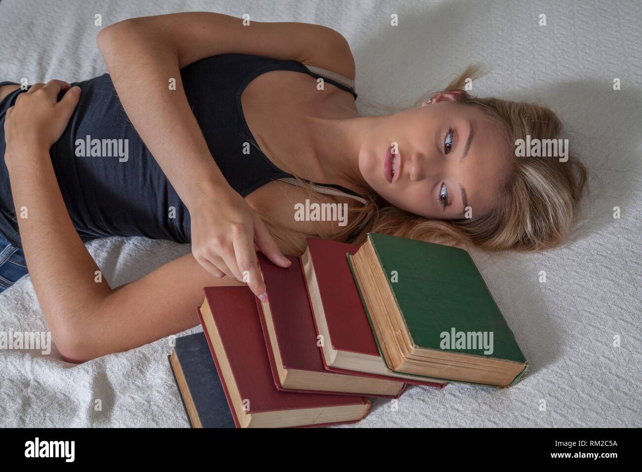 Teenage blonde Mädchen liegt auf ihrem Bett mit alten Büchern. Stockfoto