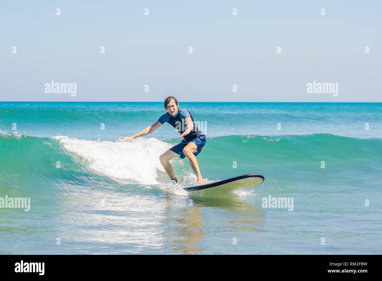 Junger Mann, Anfänger Surfer lernt Surfen auf einem Meer Schaum auf der Insel Bali Stockfoto