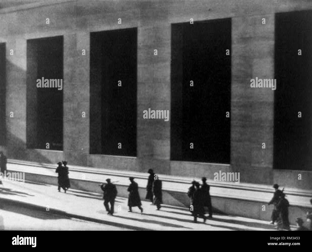 Menschen zu Fuß bis Wall Street bei starker Sonneneinstrahlung und Gebäude im Hintergrund mit großen Aussparungen, 1916. Stockfoto