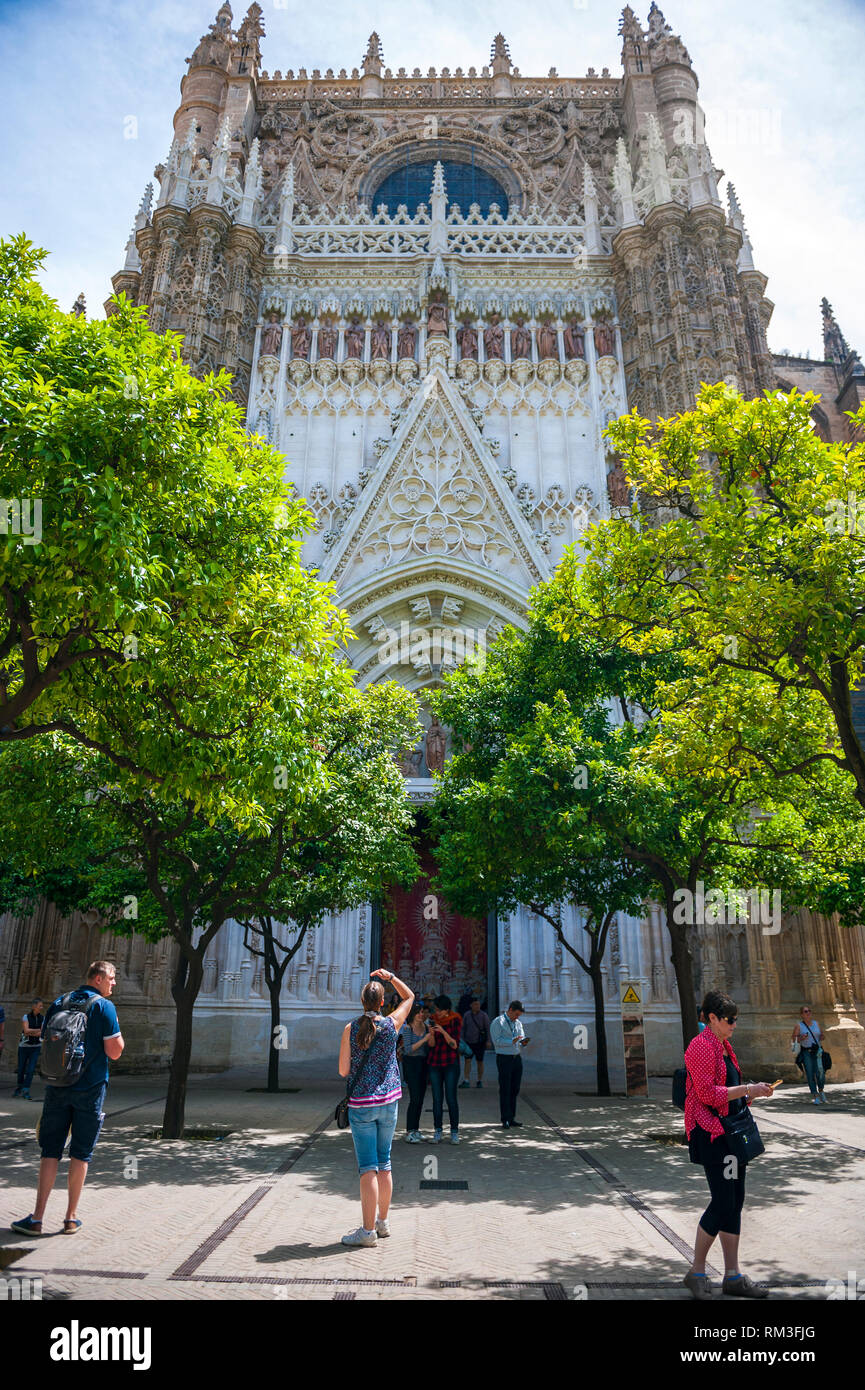 Touristen machen Fotos vom kunstvollen barocken Haupteingang der Kathedrale von Sevilla, Spanien. Stockfoto