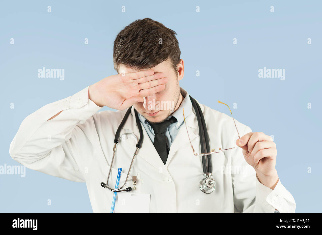 Junger Mann student Arzt schließt die Augen mit der Hand, so dass nichts ist auf einem blauen Hintergrund isoliert. Konzept der Medizin und Gesundheit, Kopfschmerzen und Stockfoto