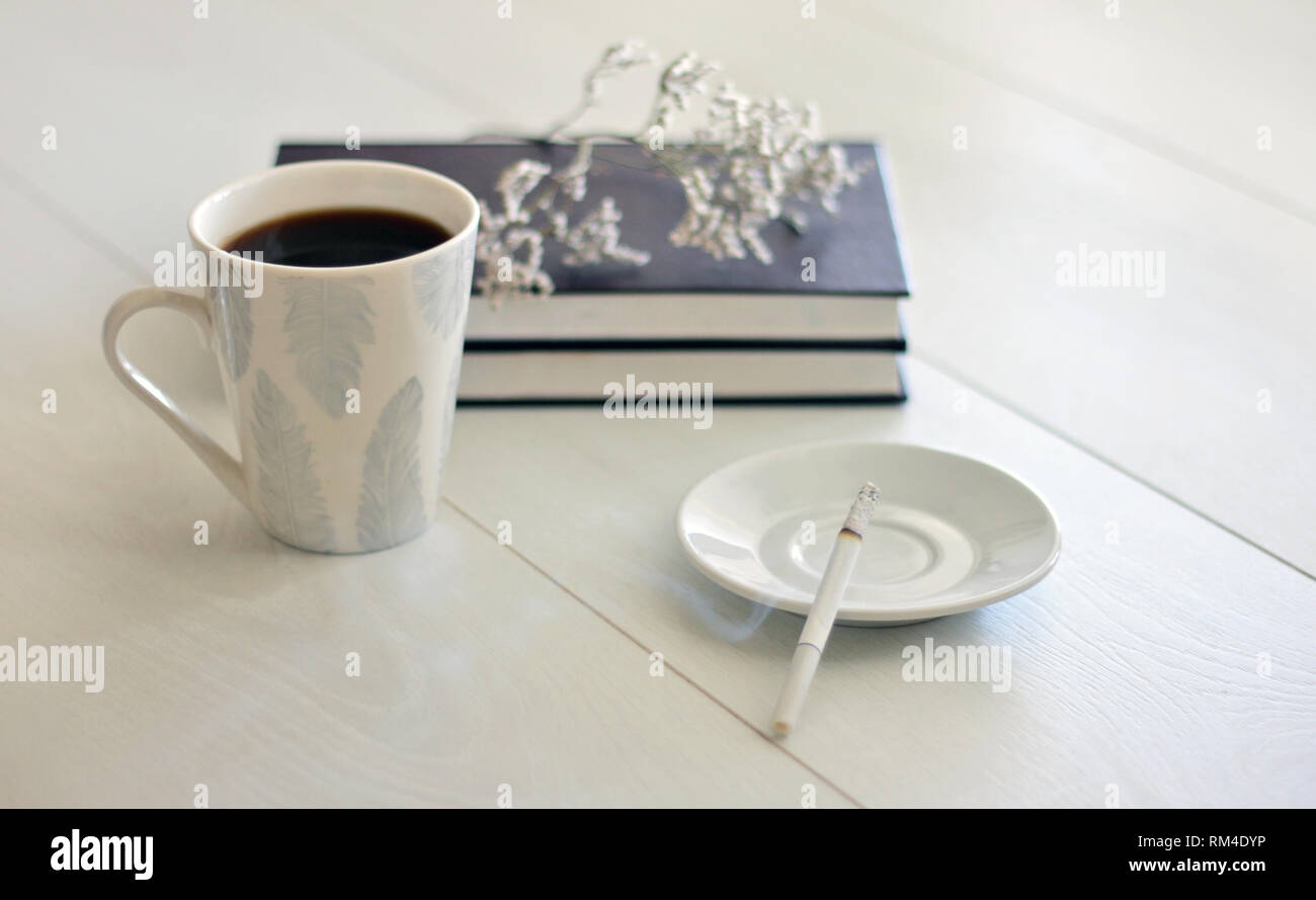 Morgenstimmung weibliche Hände eine Tasse Kaffee, ein Notebook und ein Rauchen Zigarette auf einem weißen Tisch Stockfoto