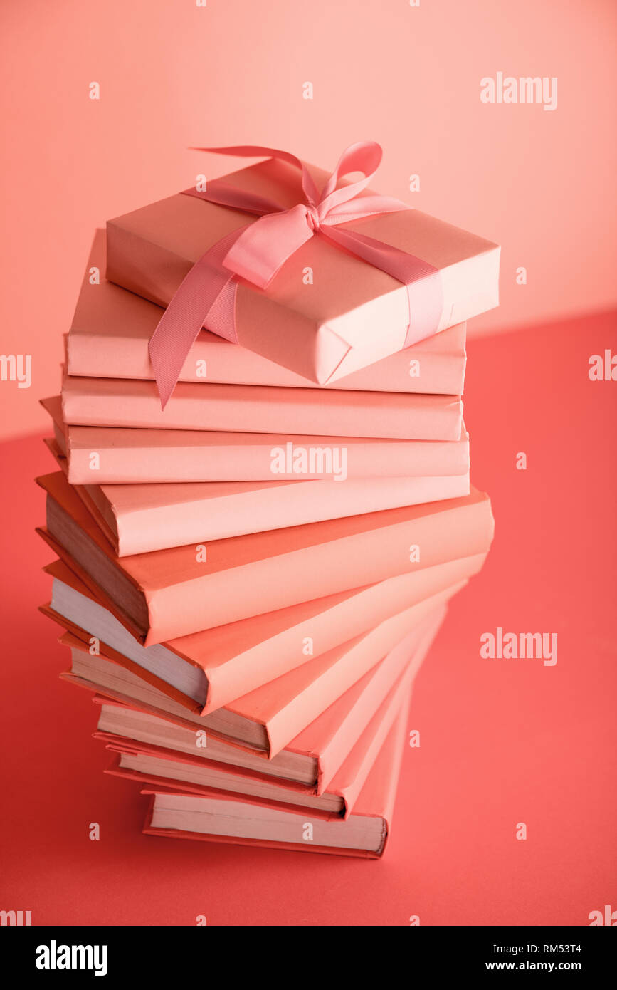 Stapel von Büchern und Geburtstagsgeschenk in lebende Koralle Farbe. Pantone-Farbe des Jahres 2019 Konzept Stockfoto