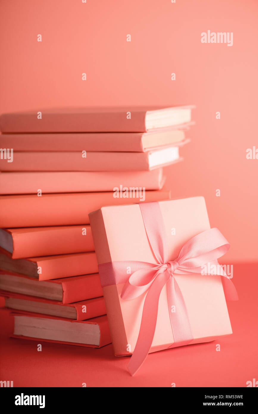 Stapel von Büchern und Geschenkbox in lebende Koralle Farbe. Pantone-Farbe des Jahres 2019 Konzept Stockfoto