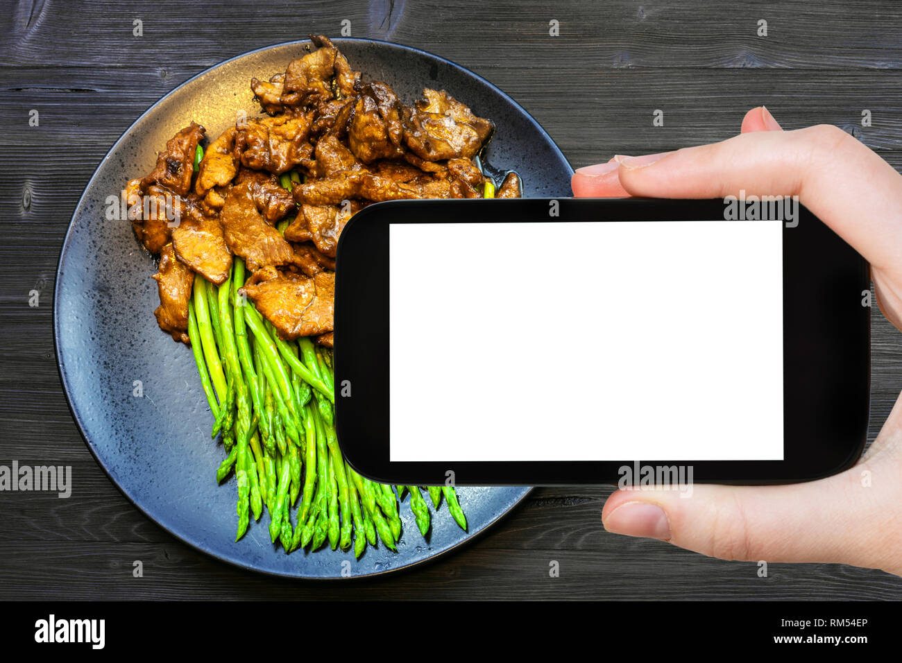 Travel Concept - touristische Fotografien der chinesischen Küche Teller von Rindfleisch gebraten in Sojasauce mit grünem Spargel auf dem Smartphone mit leeren Ausschnitt-wi Stockfoto