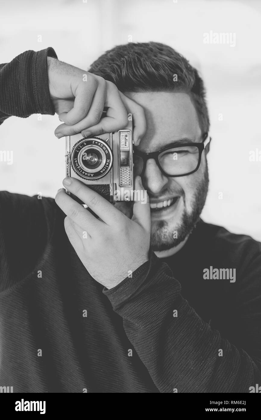 Ein Schwarz-Weiß-Porträt einer stattlichen, männlich, hipster Fotograf in Gläsern und unter Foto mit einem Vintage, 35-mm-Kamera während lächelnd Stockfoto