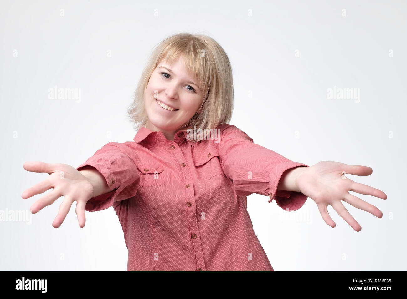 Europäische Frau in rosa Shirt mit gestreckten Händen Handshake. Sie möchte ihren Freunden zu umarmen. Stockfoto