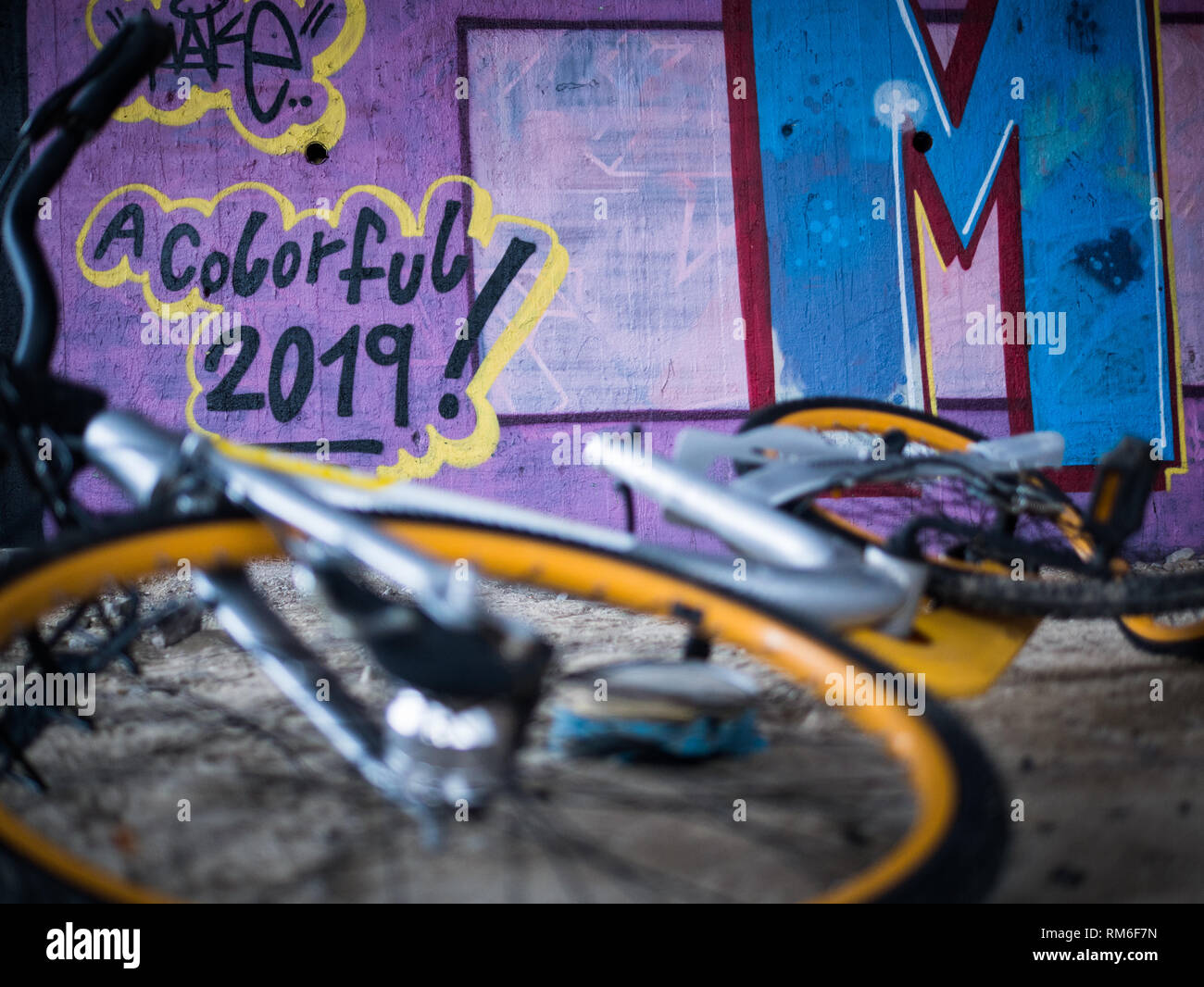 Alte gelbe Schrott, Fahrräder unter Beton Treppe mit violett Graffiti Hintergrund und Tag des neuen Jahres für eine bunte 2019 Stockfoto