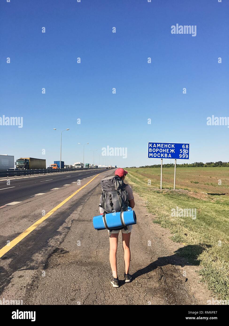 Ein reisender Mädchen mit einem Rucksack auf dem Weg geht im Sommer sonnigen Tag. Russland zurück. Stockfoto