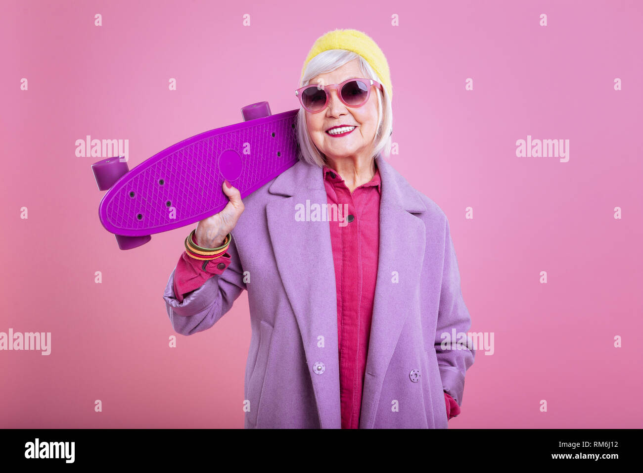 Strahlende aufgeregt Großmutter Holding hell lila Skateboard Stockfoto