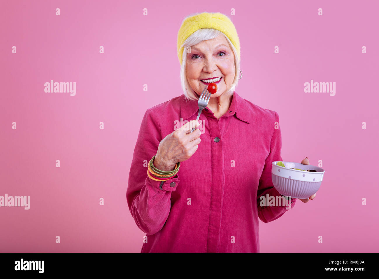 Pensionierte Frau tragen gelbe Kopf band Essen Salat Stockfoto