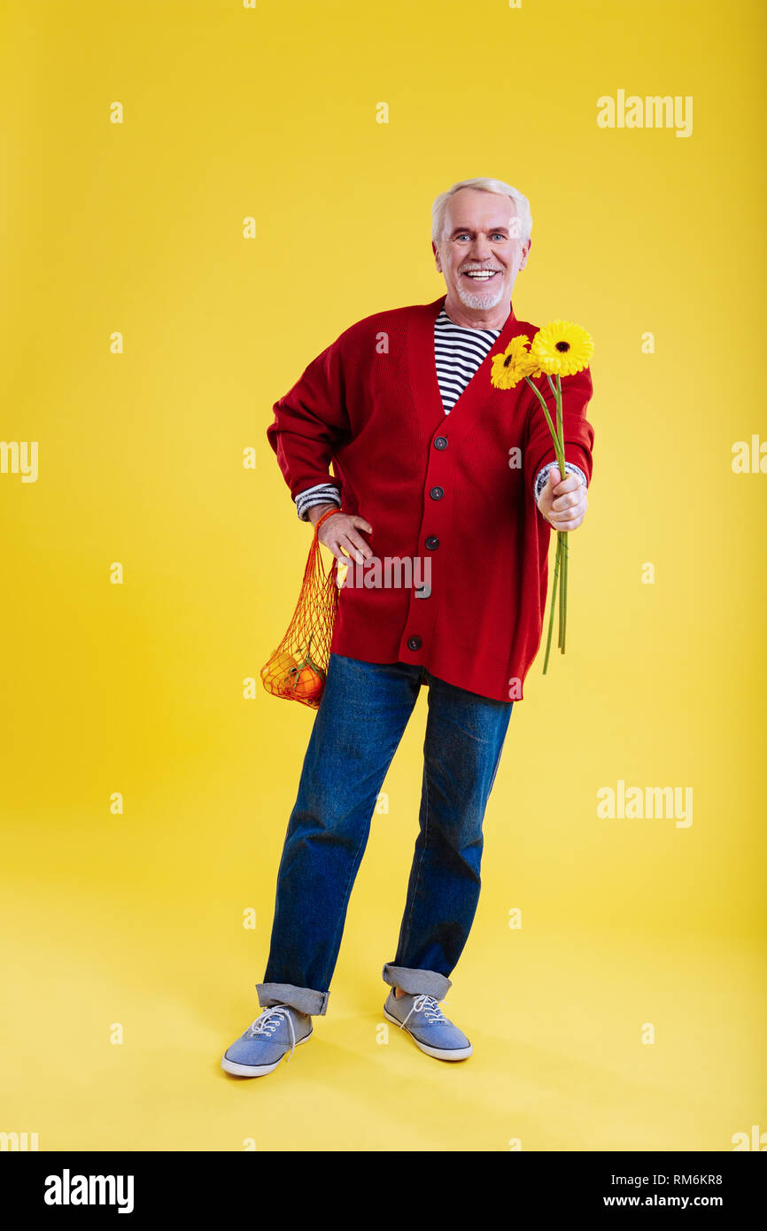 Gutherzig pensionierter Mann, der Holding Sonnenblumen für Frau Stockfoto