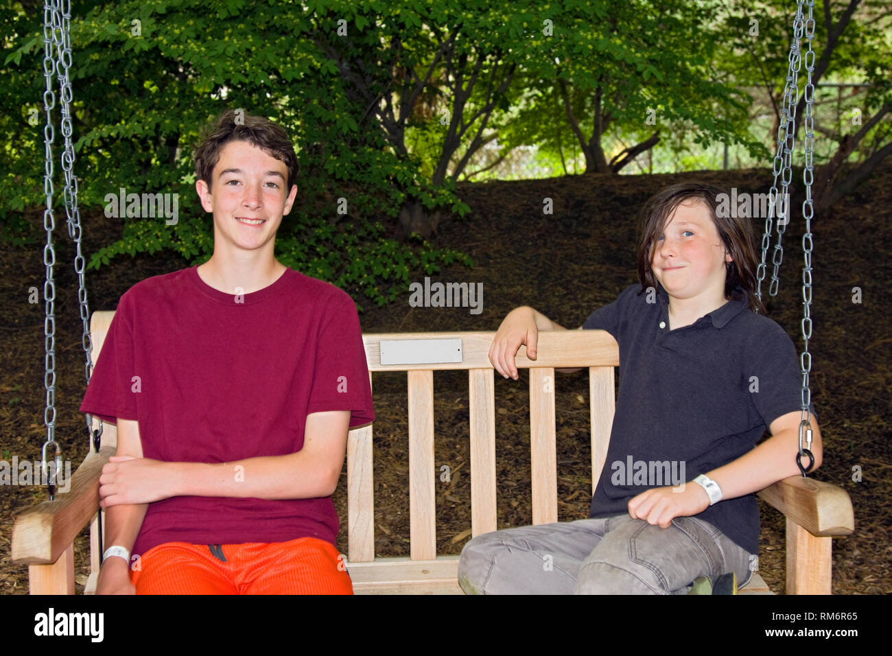 2 jugendlich Jungen; Holz Sitz schwenken; Freunde; Holz; lächelnd; Fröhlich; entspannend, Armbänder, horizontal; HERR Stockfoto