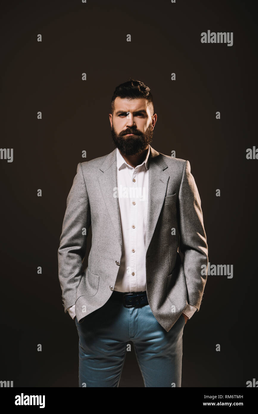 Bart Geschäftsmann in graue Jacke posiert isoliert auf Braun Stockfoto