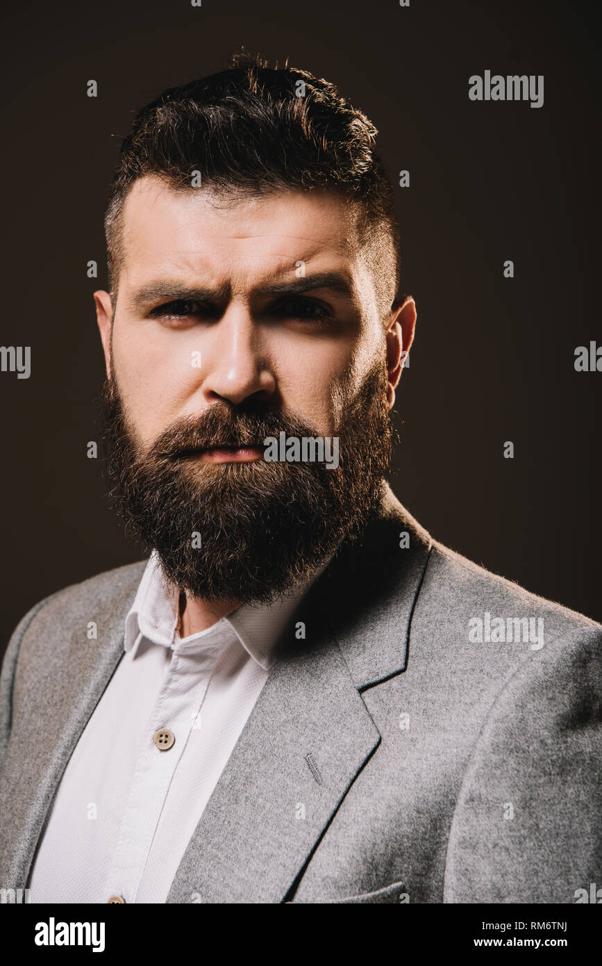 Stattliche brünette Bart Geschäftsmann in Jacke isoliert auf Braun Stockfoto