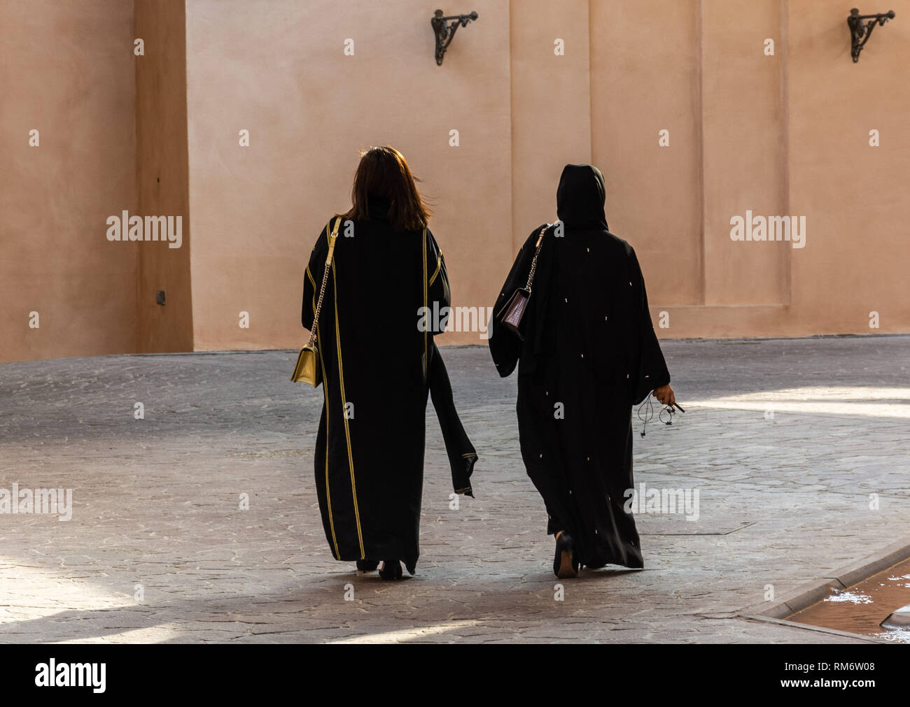 Zwei anonyme arabische Frauen tragen traditionelle islamische schwarzes Kleid, aber auch von der Rückseite. Eins mit und eins mit unbedeckten Kopf. Stockfoto