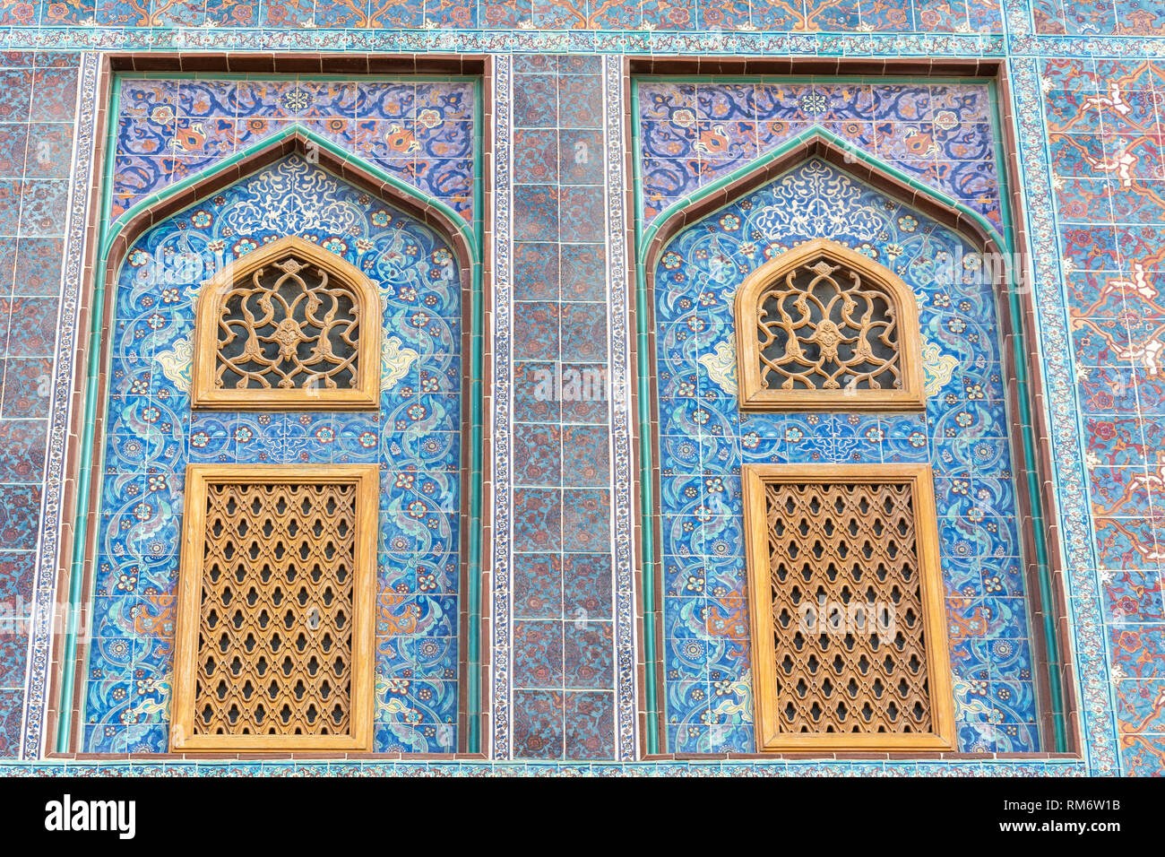 Die traditionelle arabische mashrabiya Fenster auf einen gefliesten Wand mit geschnitztem Holz Gitterwerk in Katar eingeschlossen. Stockfoto