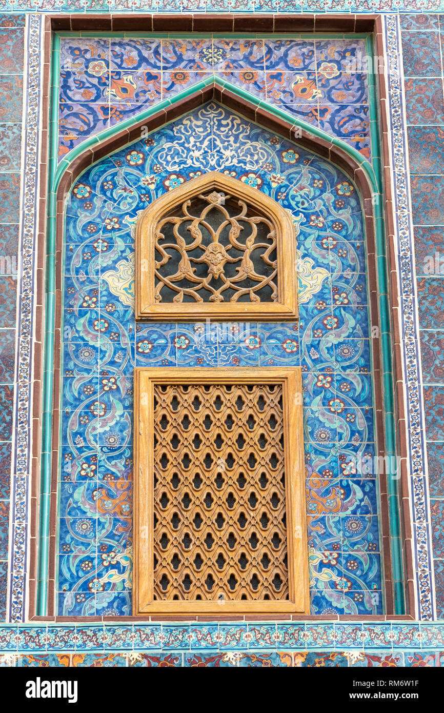 Die traditionelle arabische mashrabiya Fenster auf einen gefliesten Wand mit geschnitztem Holz Gitterwerk in Katar eingeschlossen. Stockfoto