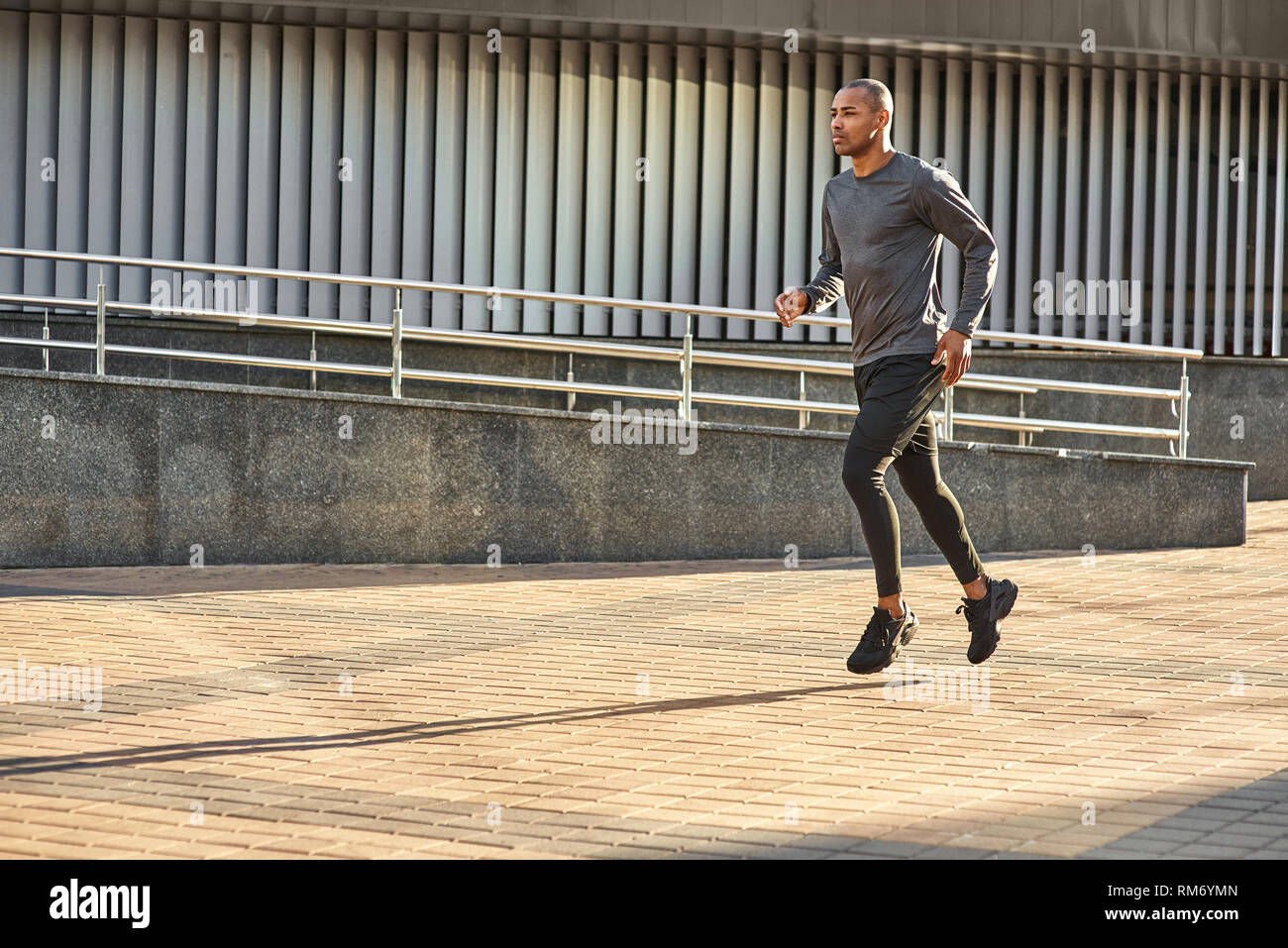 Er ist immer in der guten Form in voller Länge Porträt von starken und sportlichen afrikanischer Mann seine cardio Training genießen in einem sonnigen Morgen. Von der Seite. Von der Seite. Gesunde Lebensweise. Sport und Motivation Konzept. Stockfoto