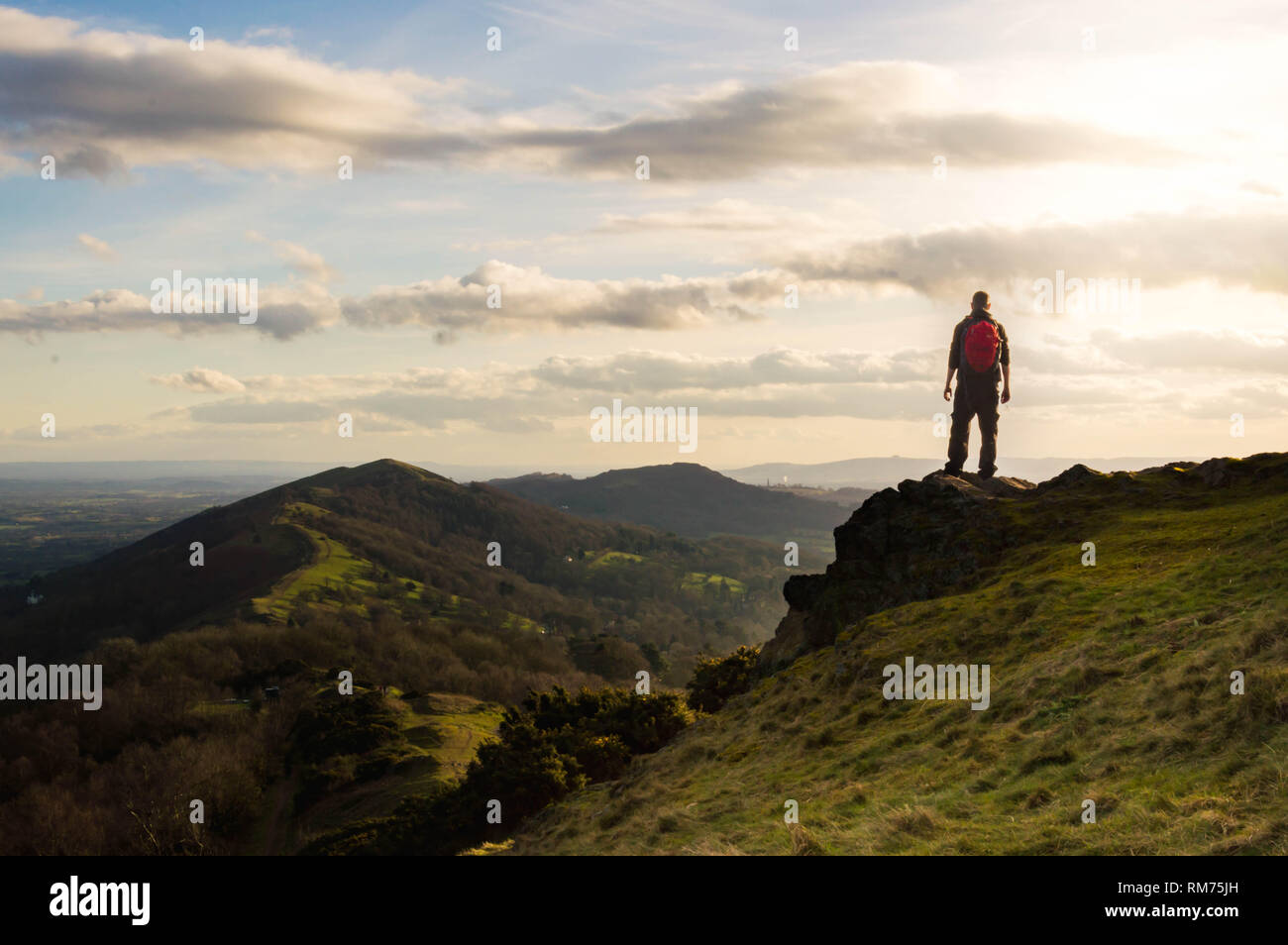 Ein einsamer Wanderer mit Blick über den Grat der Malvern Hills auf einer sonnigen Winter am Nachmittag. Malvern Hills, England. Stockfoto