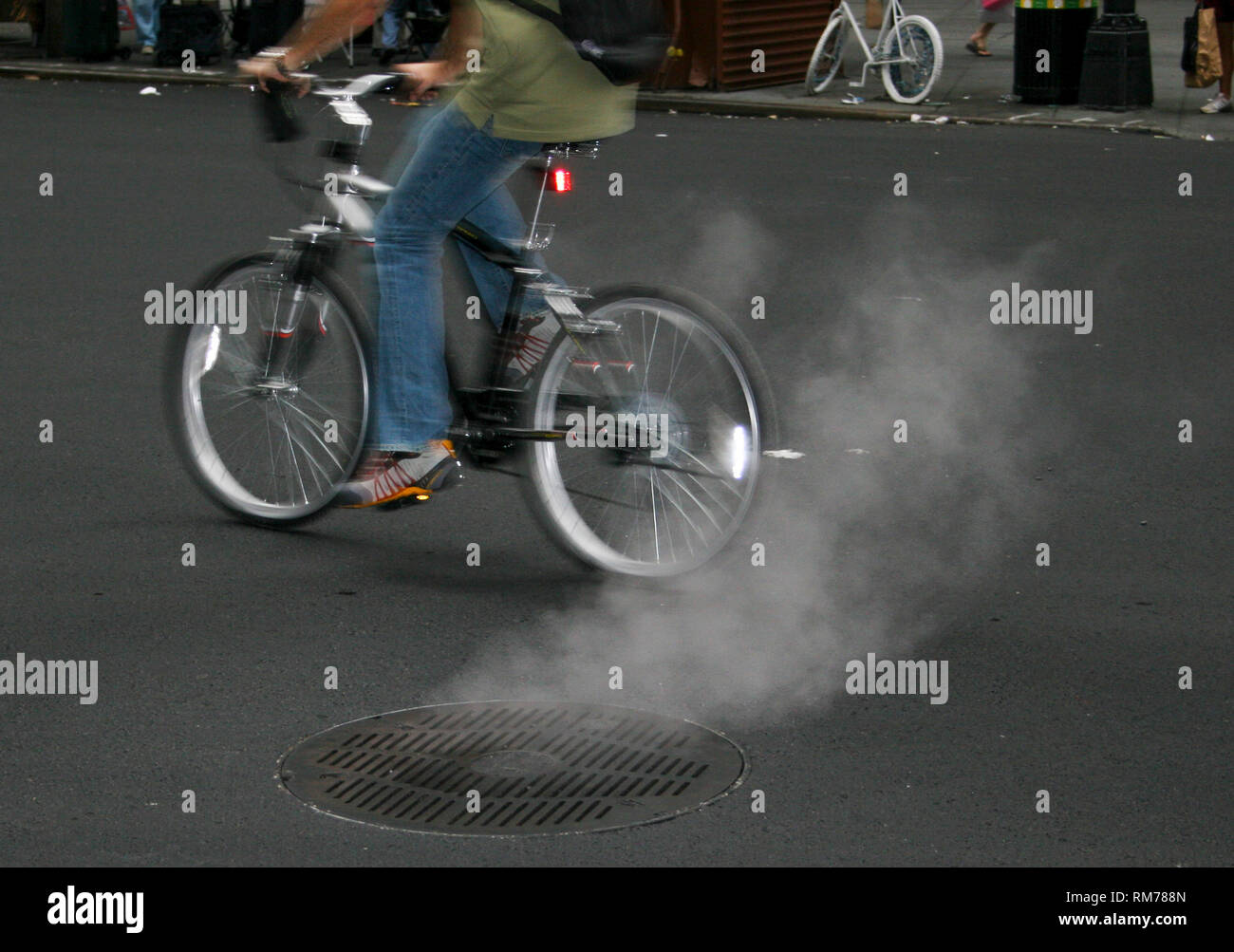 Radfahrer in New York Pässe rauchen Mannloch Stockfoto