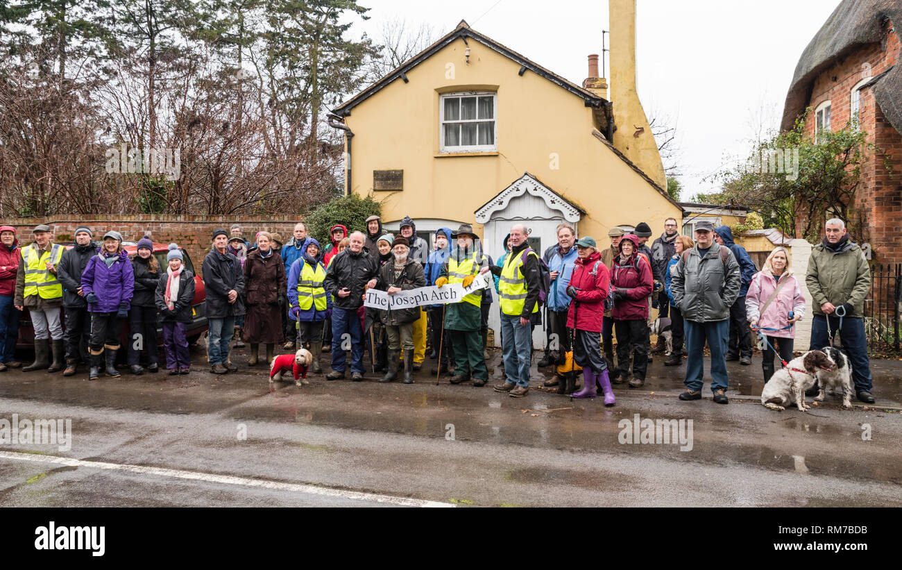 Wanderer in Outdoor Bekleidung zu Beginn des Joseph Bogen 100 Fuß außerhalb seiner Hütte im Dorf Barford, mit einem Banner. Stockfoto