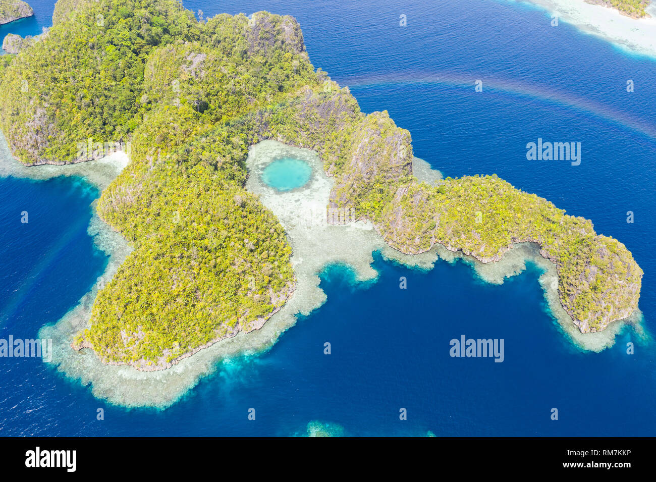 Ein Regenbogen erscheint oben ein robustes Kalkstein Insel in Raja Ampat, Indonesien. Dieser abgelegene, tropische Region ist für seine marine Artenvielfalt bekannt. Stockfoto