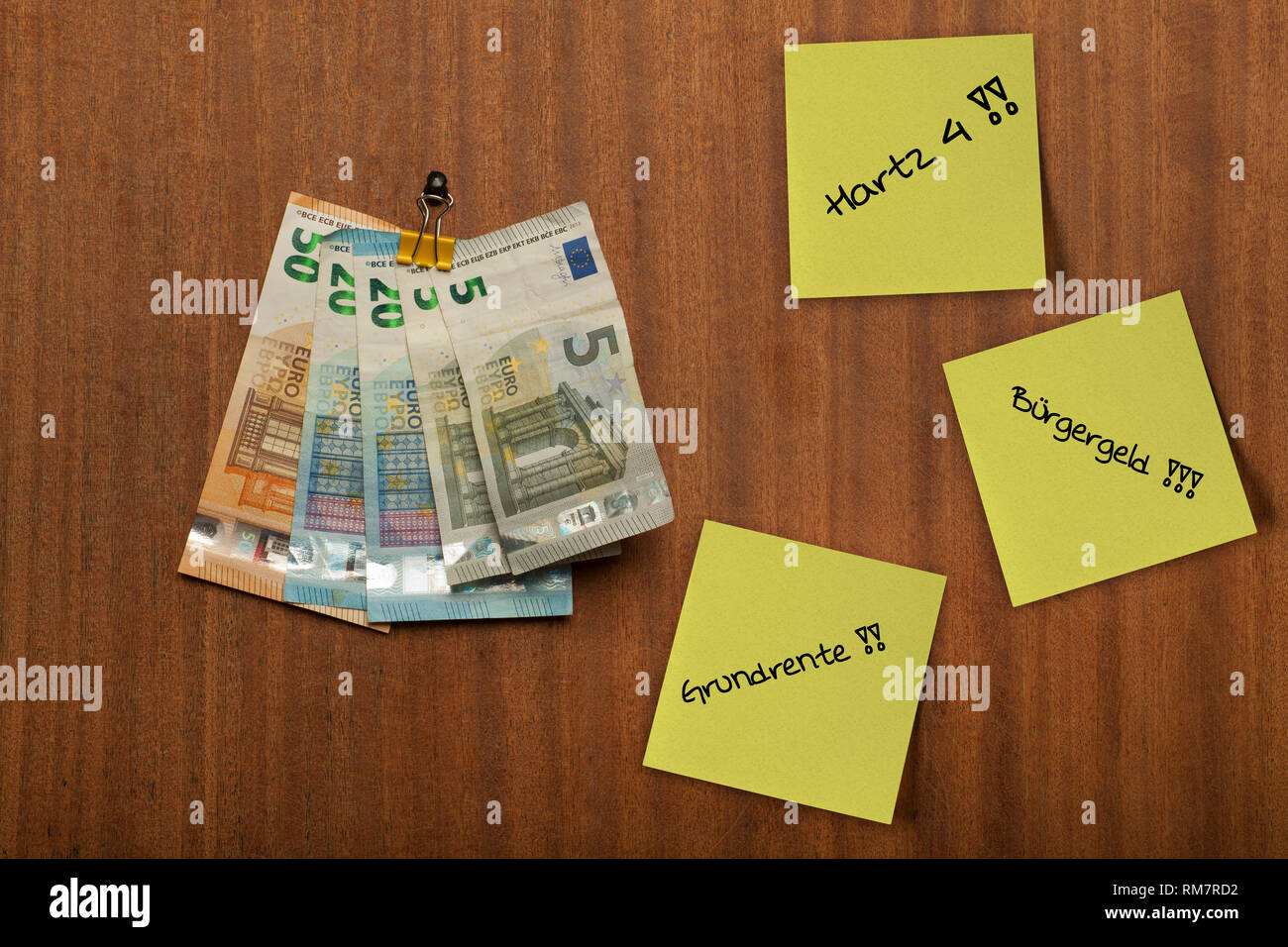 Einige Stücke Papier, Post ihre hängen an der Holz- Pin Board und euro Geld, Notizen, mit den deutschen Worten Hartz 4, Buergergeld, Grundrente geschrieben Stockfoto