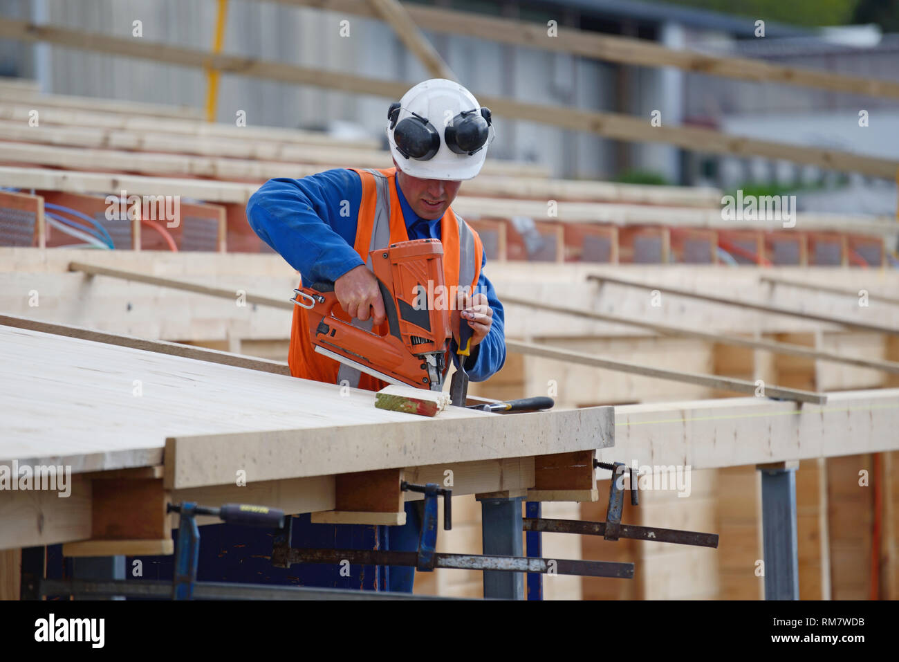 Ein Bauherr verwendet ein Bolzenschußgerät, um sichere Holz auf der Veranda des Neubaus Stockfoto