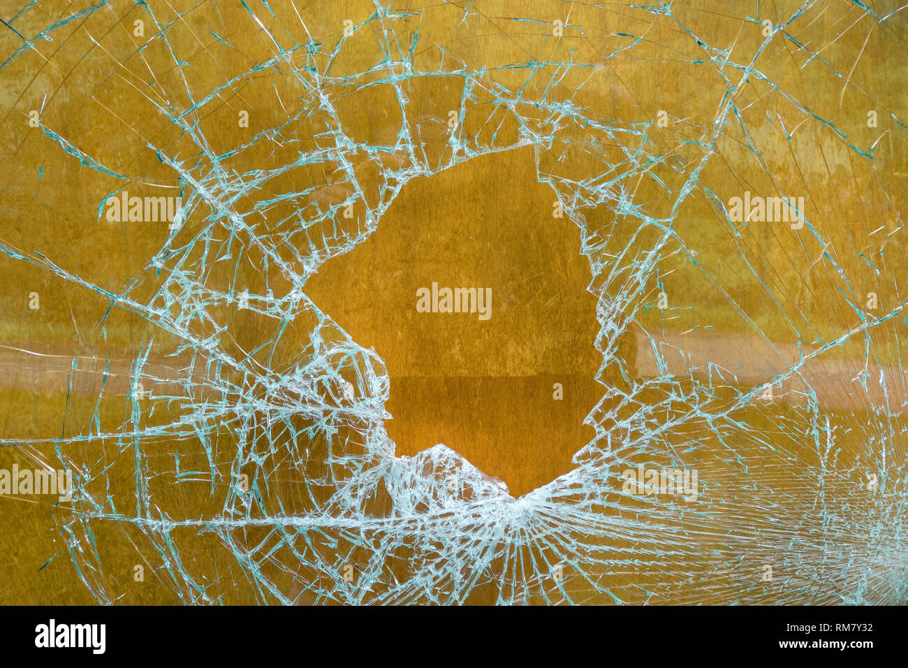 Zerschlagene Glasscheibe vor braunem Holz Stockfoto