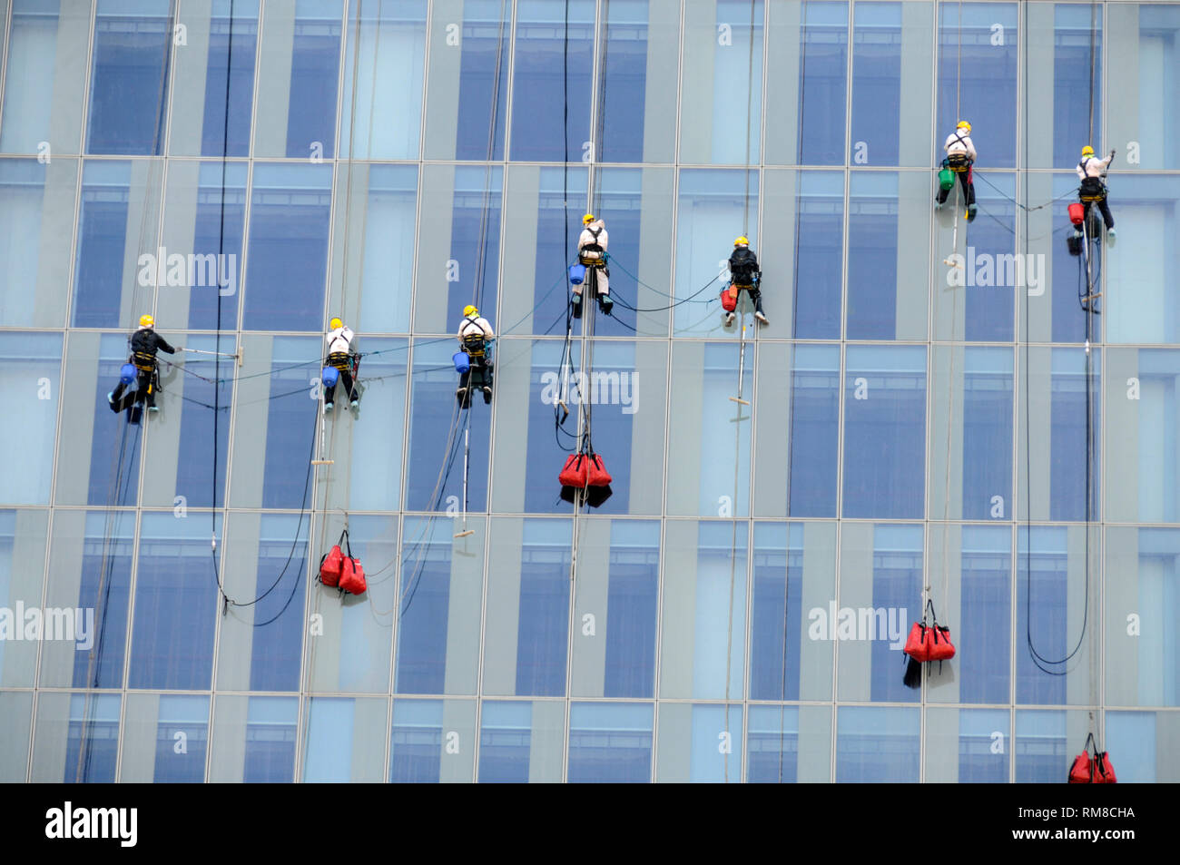 Eine Gruppe von asiatischen Fensterputzer durch Kletterseile im Finanzzentrum von Dubai in den Vereinigten Arabischen Emiraten (VAE) unterstützt. Stockfoto