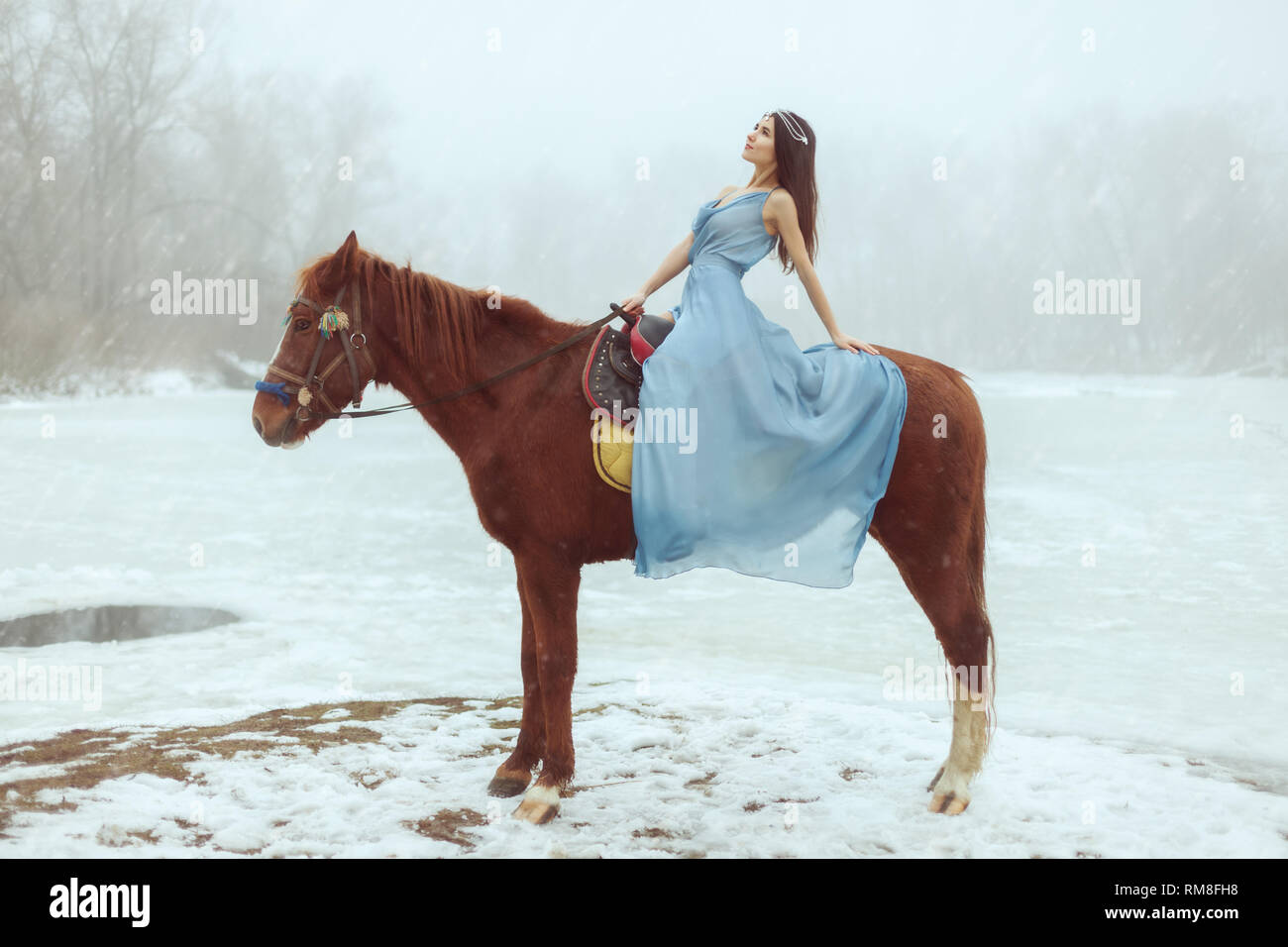 Junge schöne Brünette reiten ein Pferd von einem zugefrorenen See. Stockfoto