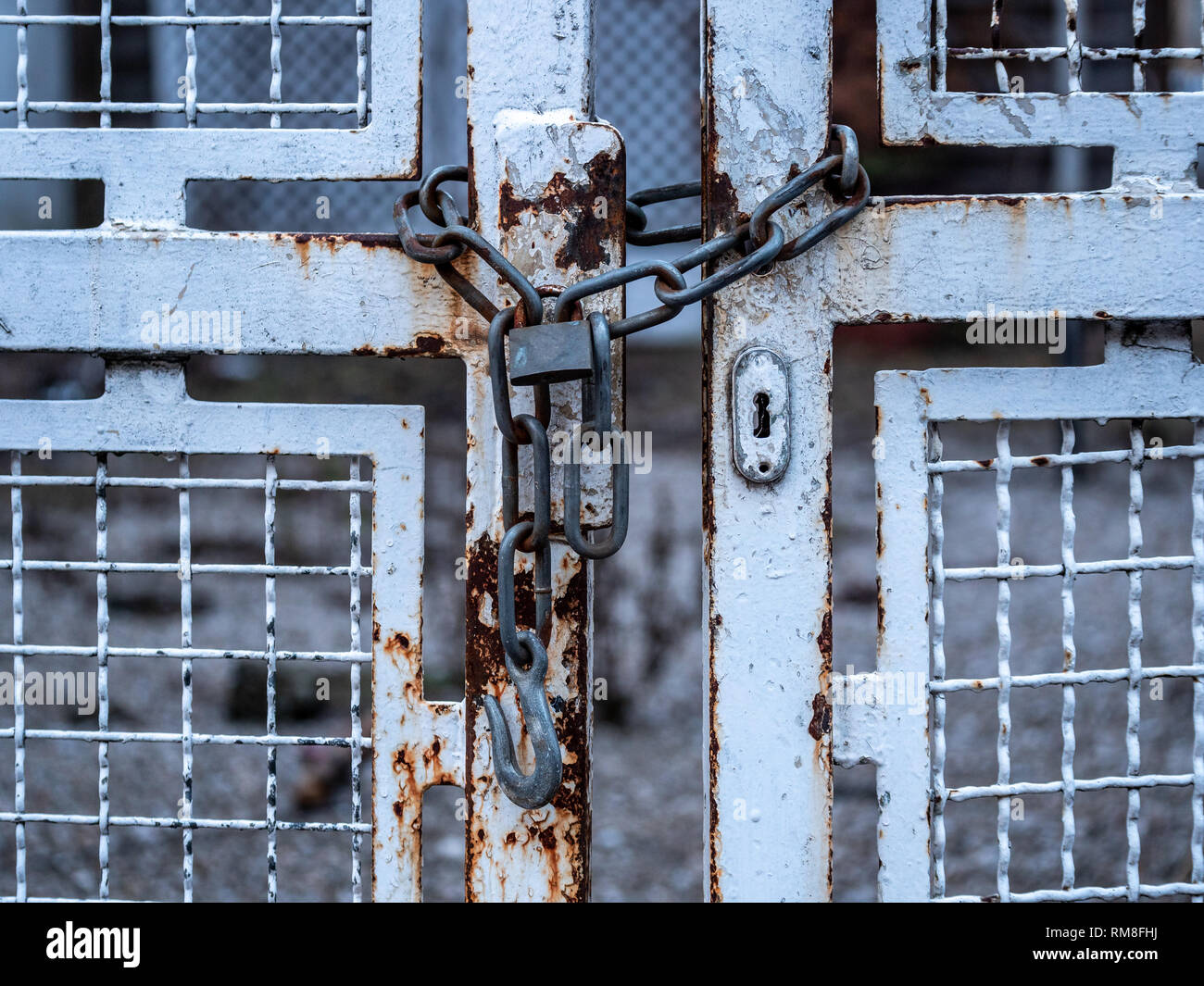 Bild der alten Kette mit Vorhängeschloss und weiße schmiedeeiserne Tor. close-up Stockfoto