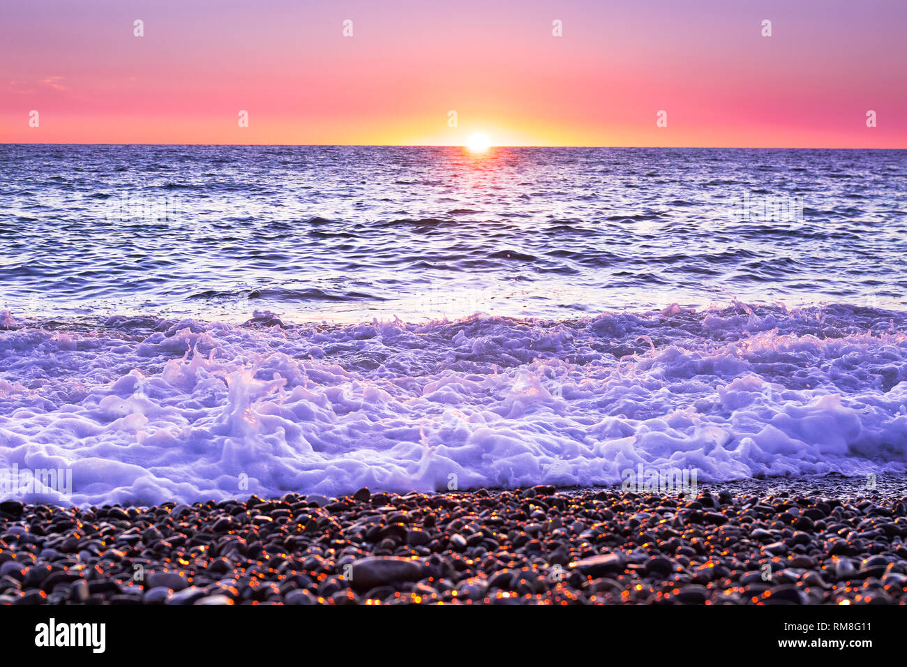 Lila Landschaft mit Blick auf das Meer und den Sonnenuntergang. Abendsonne über Meer. schöne Landschaft mit Sonnenaufgang über dem See Panoramaaussicht Stockfoto
