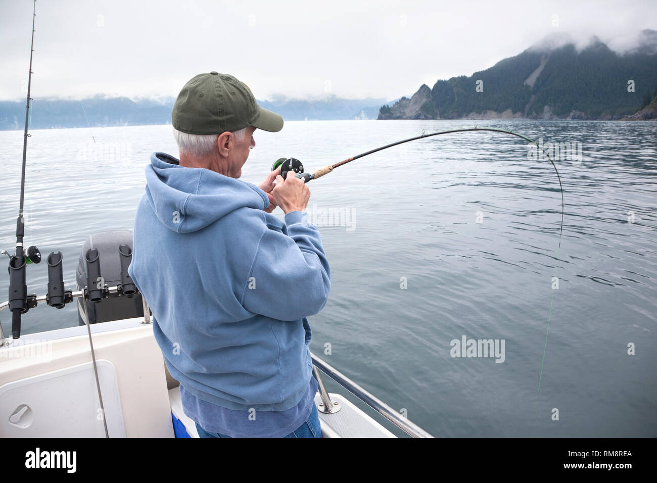 Ein älterer Fischer kämpft ein Fisch im Ozean in der Nähe von Seward, Alaska Stockfoto