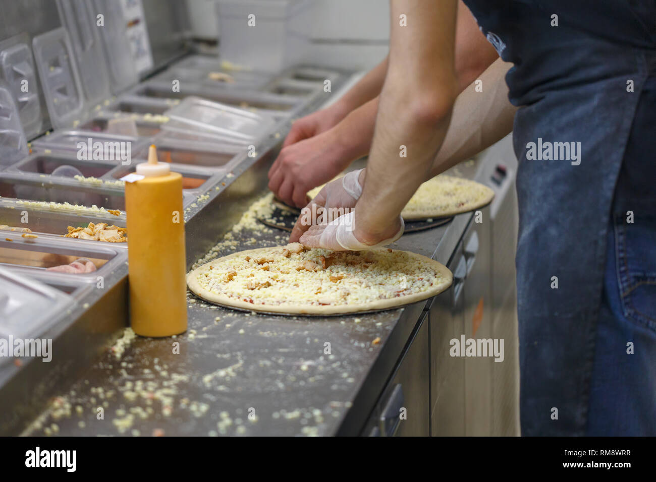 Männer machen verschiedene Pizzen im Fast-Food-Restaurant Stockfoto