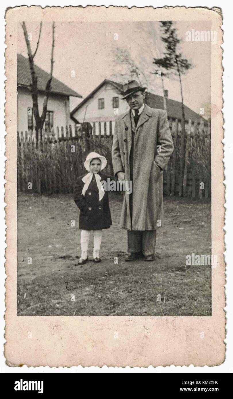 Retro-Foto zeigt Vater und kleine Tochter gehen für einen Spaziergang. Vater und kleines Mädchen entspannen und genießen Zeit im Freien. Schwarz-weißer Jahrgang.60s. Stockfoto