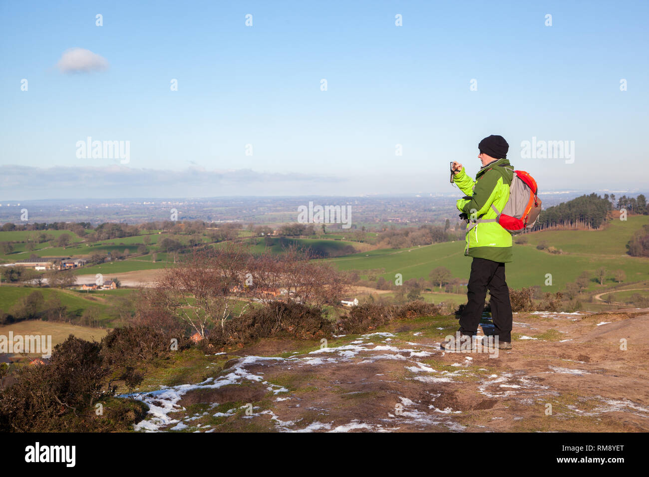 Mann mit Rucksack genießen den Blick auf die Cheshire Plain im Winter aus dem Sandstein trail auf Bickerton Hügel Cheshire Stockfoto