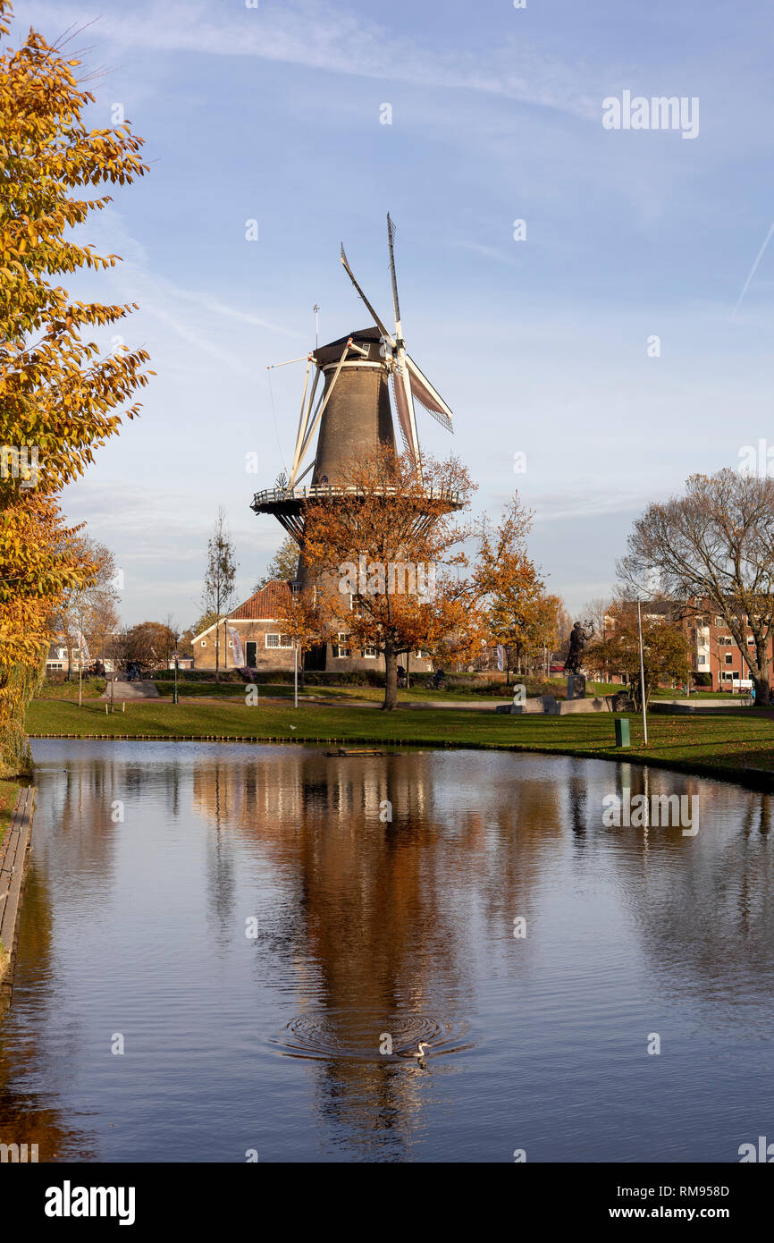 Vertikale Ansicht einer Windmühle in städtischen Umgebung in den Kanal mit klarem, blauem Himmel und Vogel Erstellen von Kreisen wider Stockfoto