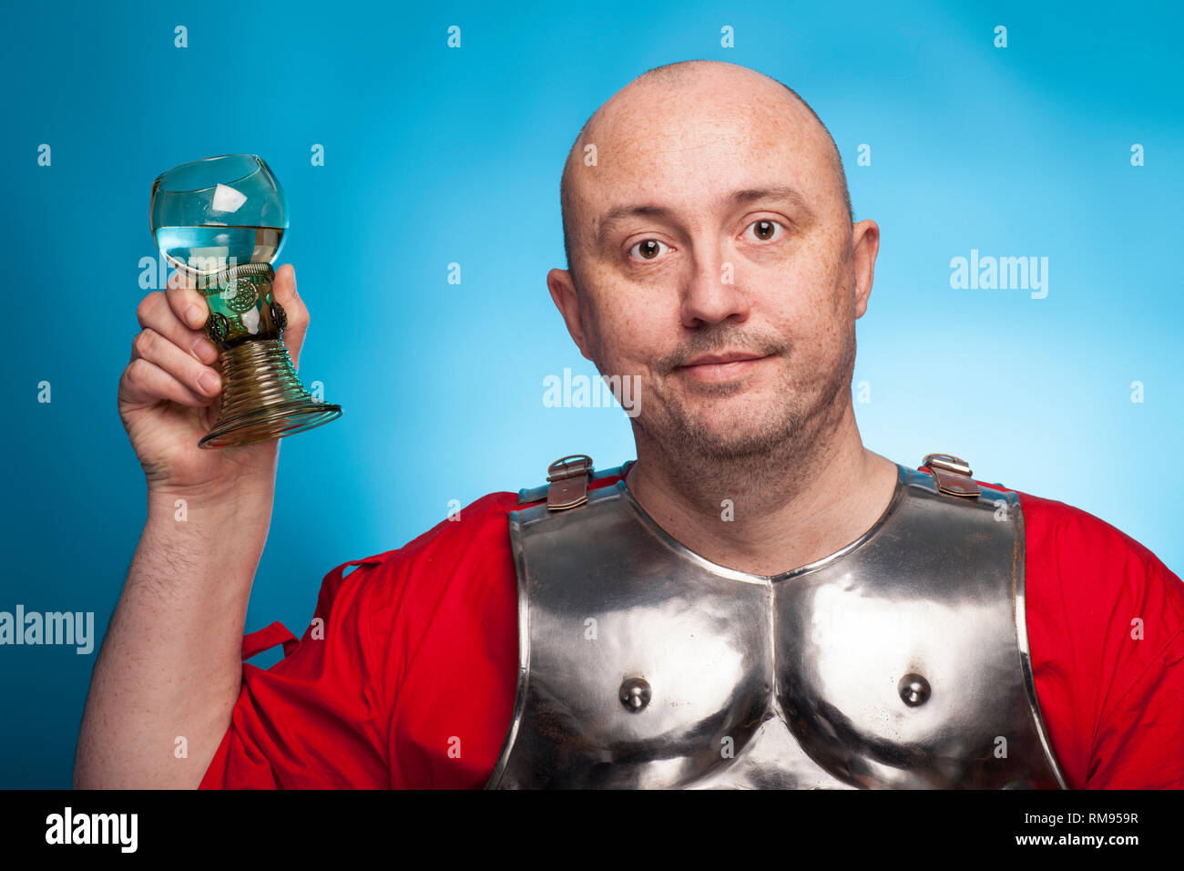 Ein römischer Soldat betrunken mit einem Glas Wein auf dem blauen Hintergrund. Stockfoto
