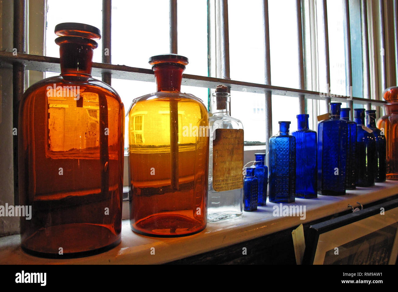 Farbige viktorianischen Medizin Flaschen auf einem Regal, blau, orange, gelb, Glas Stockfoto