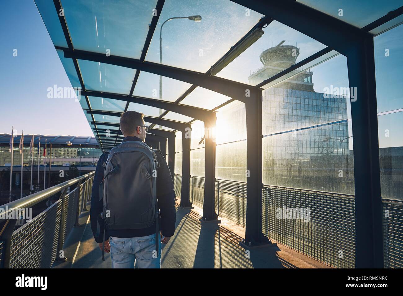 Junger Mann mit Rucksack zu Fuß zum Flughafen Terminal bei Sonnenuntergang. Stockfoto
