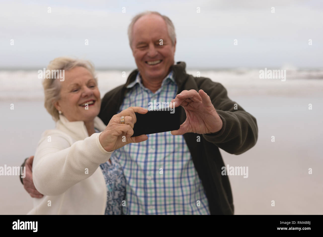 Gerne älteres Paar unter selfie mit Handy am Strand Stockfoto