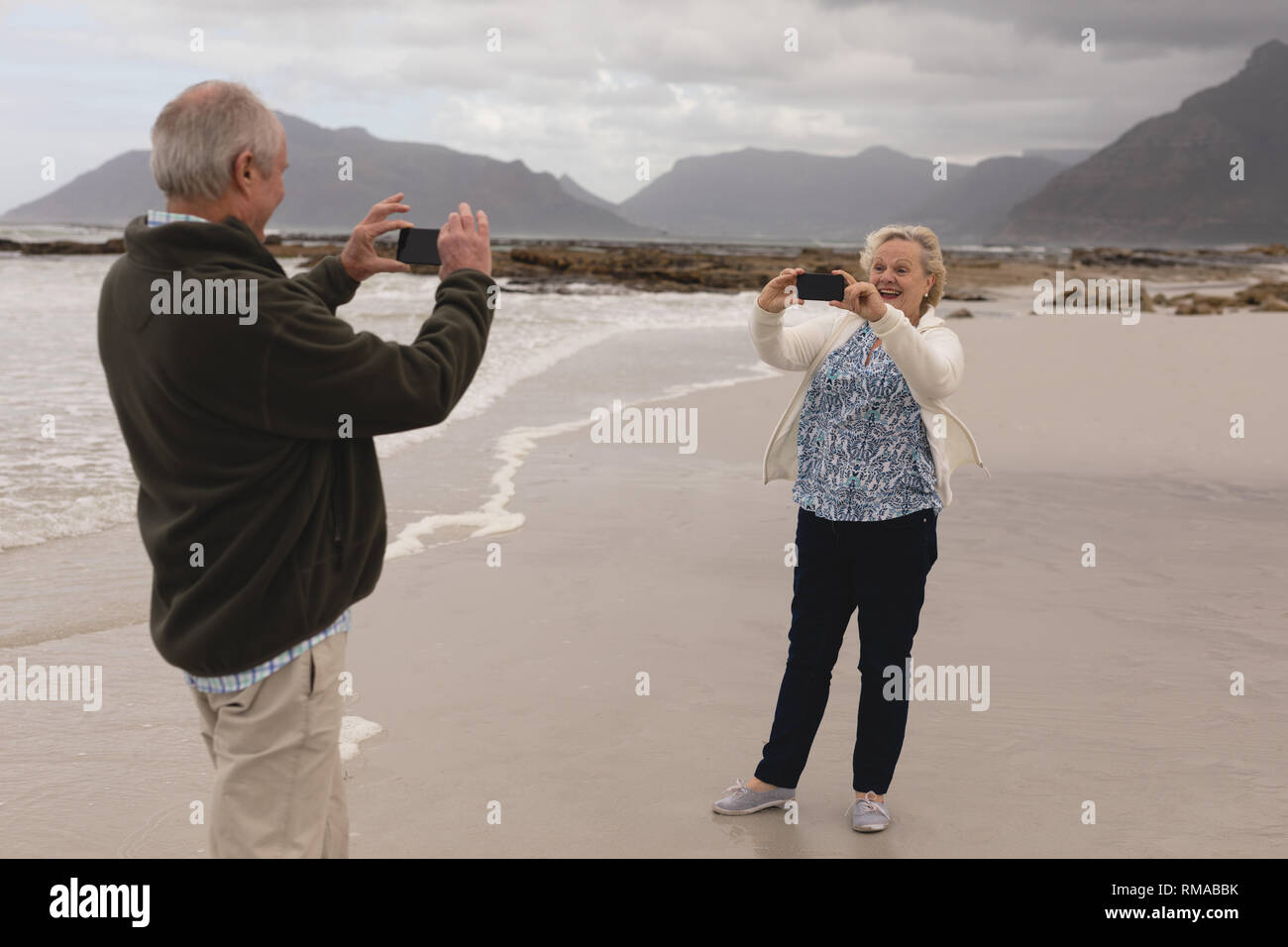 Senior Paar unter Foto mit Handy am Strand Stockfoto