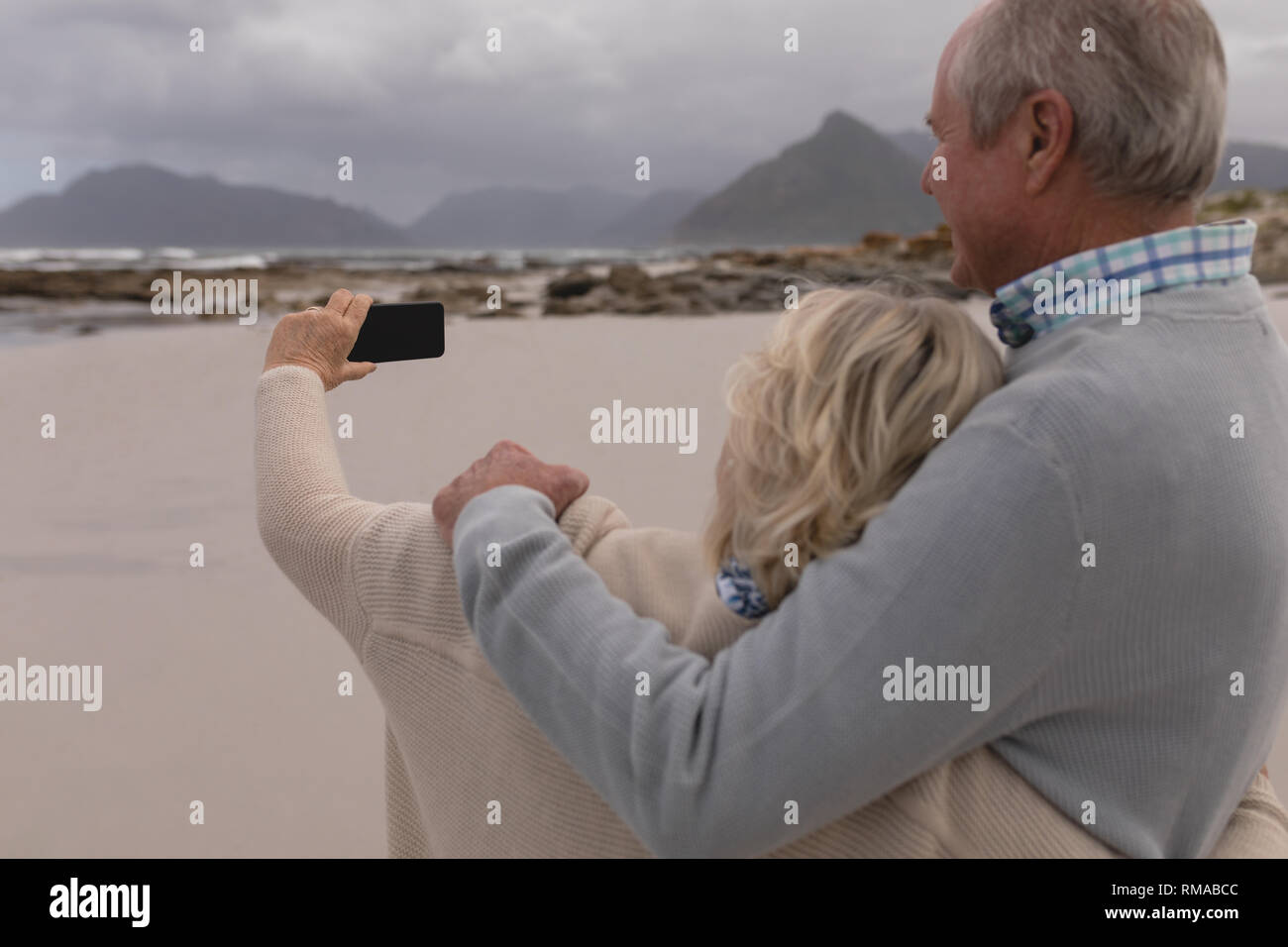 Gerne älteres Paar unter selfie mit Handy stehen am Strand Stockfoto