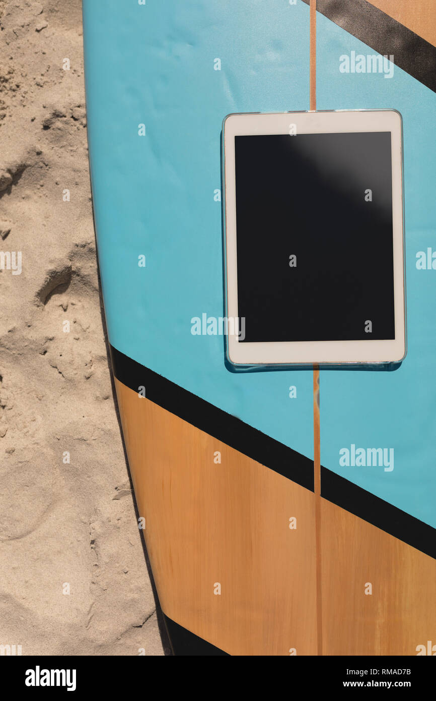 Digitale Tablette auf Surfboard am Strand Stockfoto