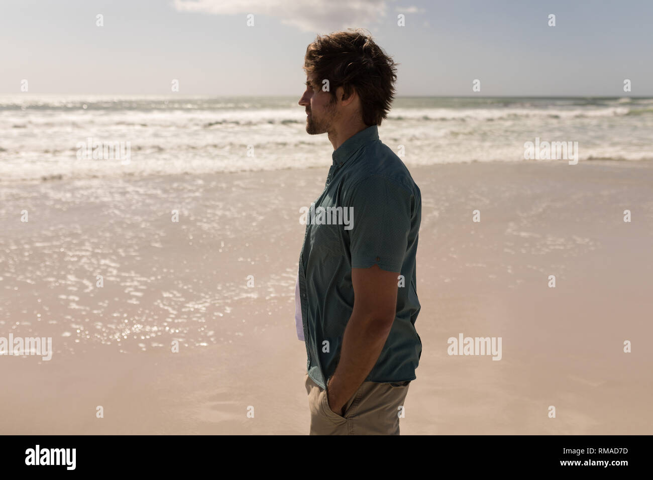 Junger Mann mit der Hand in der Tasche stehen am Strand. Stockfoto